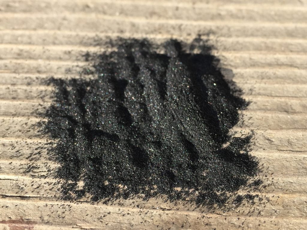 A pile of black charcoal powder on a rough, lined surface