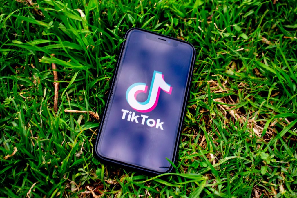 a smartphone lying on some grass with the tiktok logo on the screen