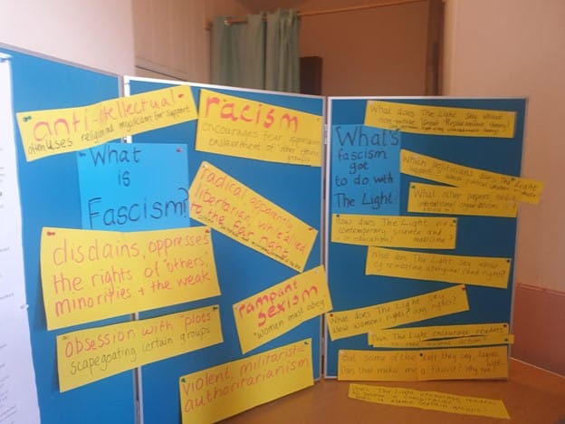  A photo of the board with questions and answers on it taken by the author. The question "What is fascism?" has answers pinned saying things like "rampant sexism" and "racism". 