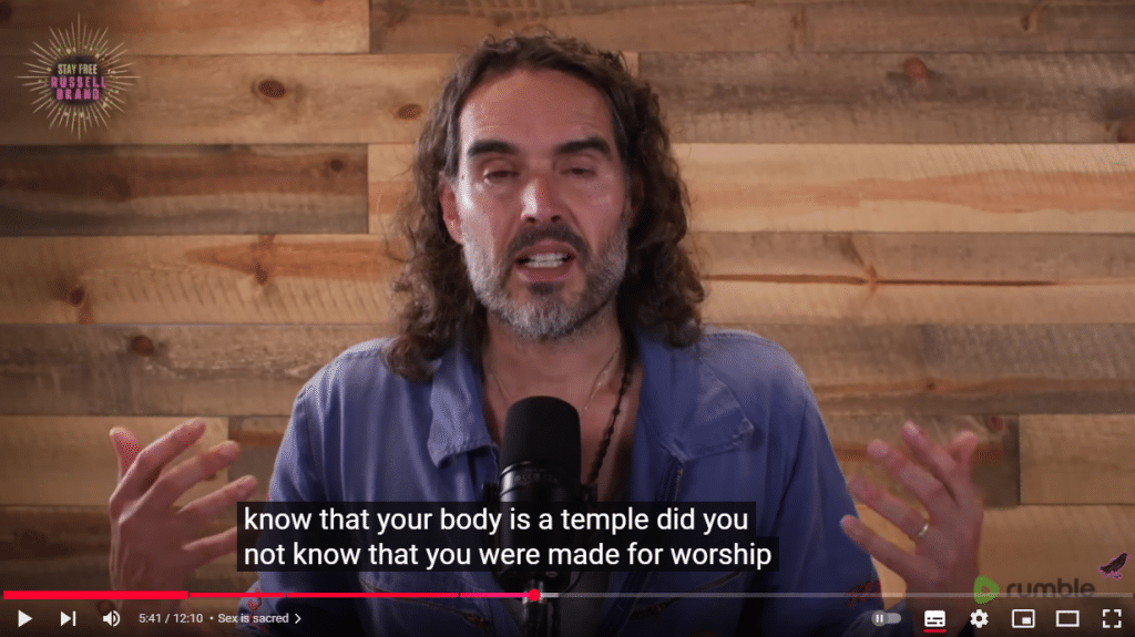 A screenshot of a YouTube video. Russell Brand talking into a microphone. The subtitles read "know that your body is a temple did you not know that you were made for worship".